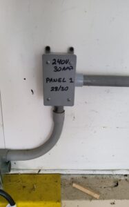 Electrical technicians installing a 240V connection for an EV charger using PVC conduit