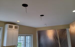 Electricians installing fixtures for custom lighting and outlets in the kitchen ceiling
