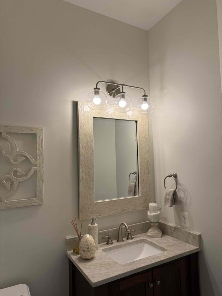 Deshaies Electrical Services replacing bathroom light fixtures and installing globe lighting above the mirror