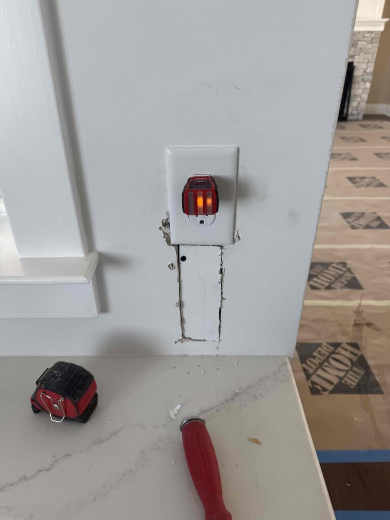 Deshaies Electrical Services inspecting a power outlet and preparing for wiring adjustments