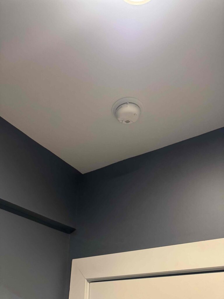 Deshaies Electrical Services installing a smoke detector as part of basement safety enhancements in the electrical project